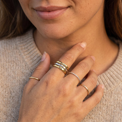Tunn stapelbar namnring – guld & silver – kombinerad med andra ringar, buren